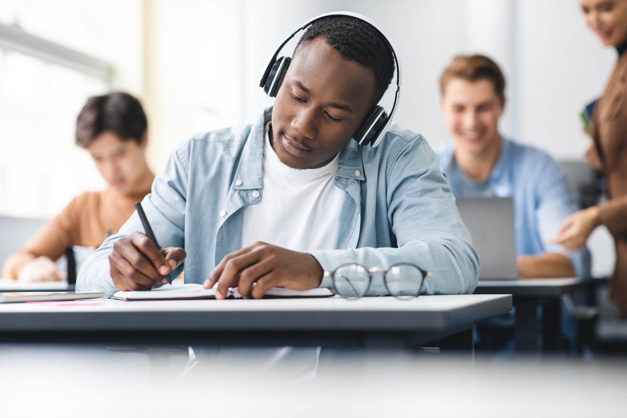 black man sitting at desk in classroom writing exam