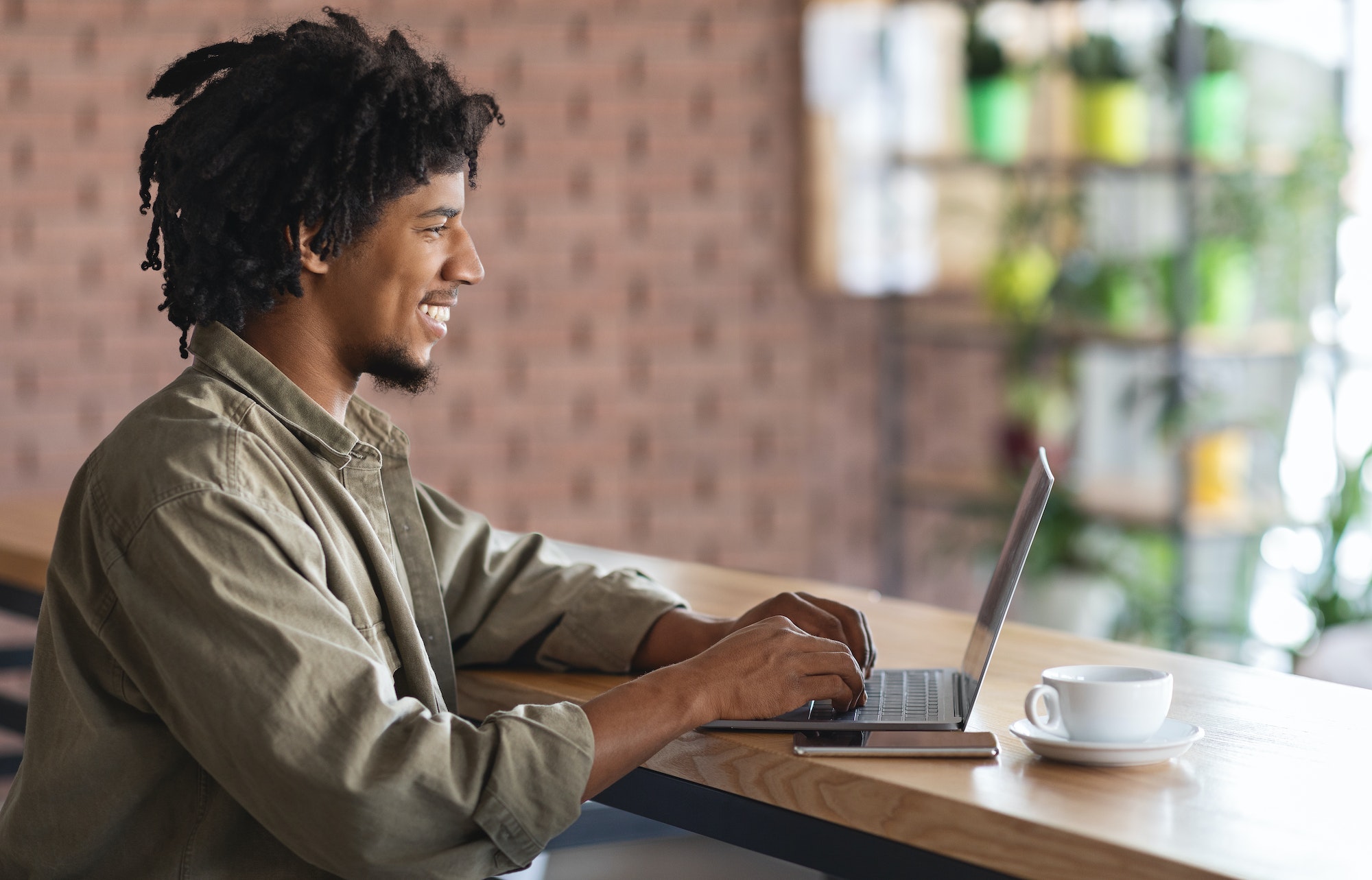 remote work young african american freelancer guy working with laptop at cafe