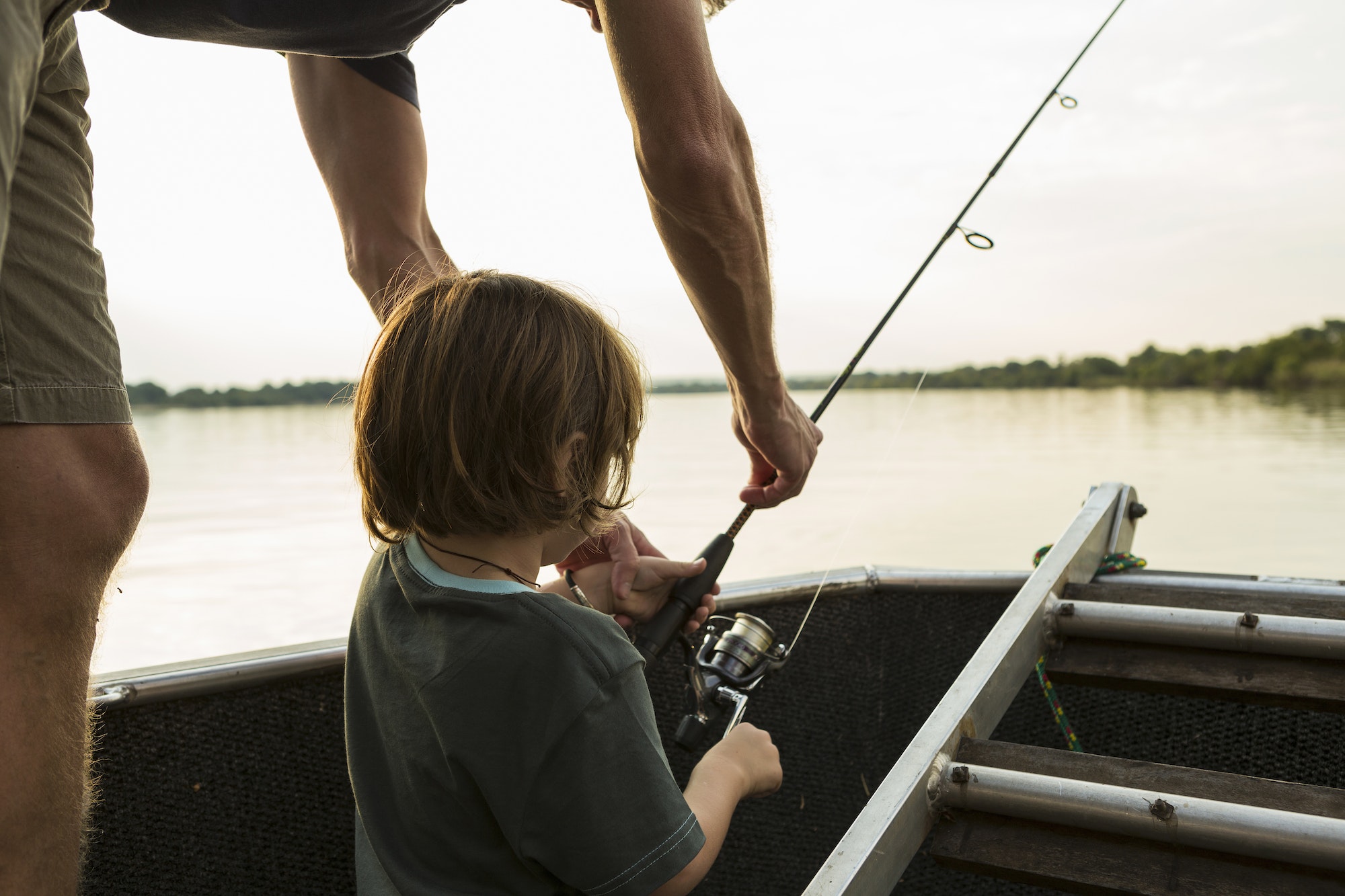 a five year old boy fishing from a boat on the zambezi river botswana