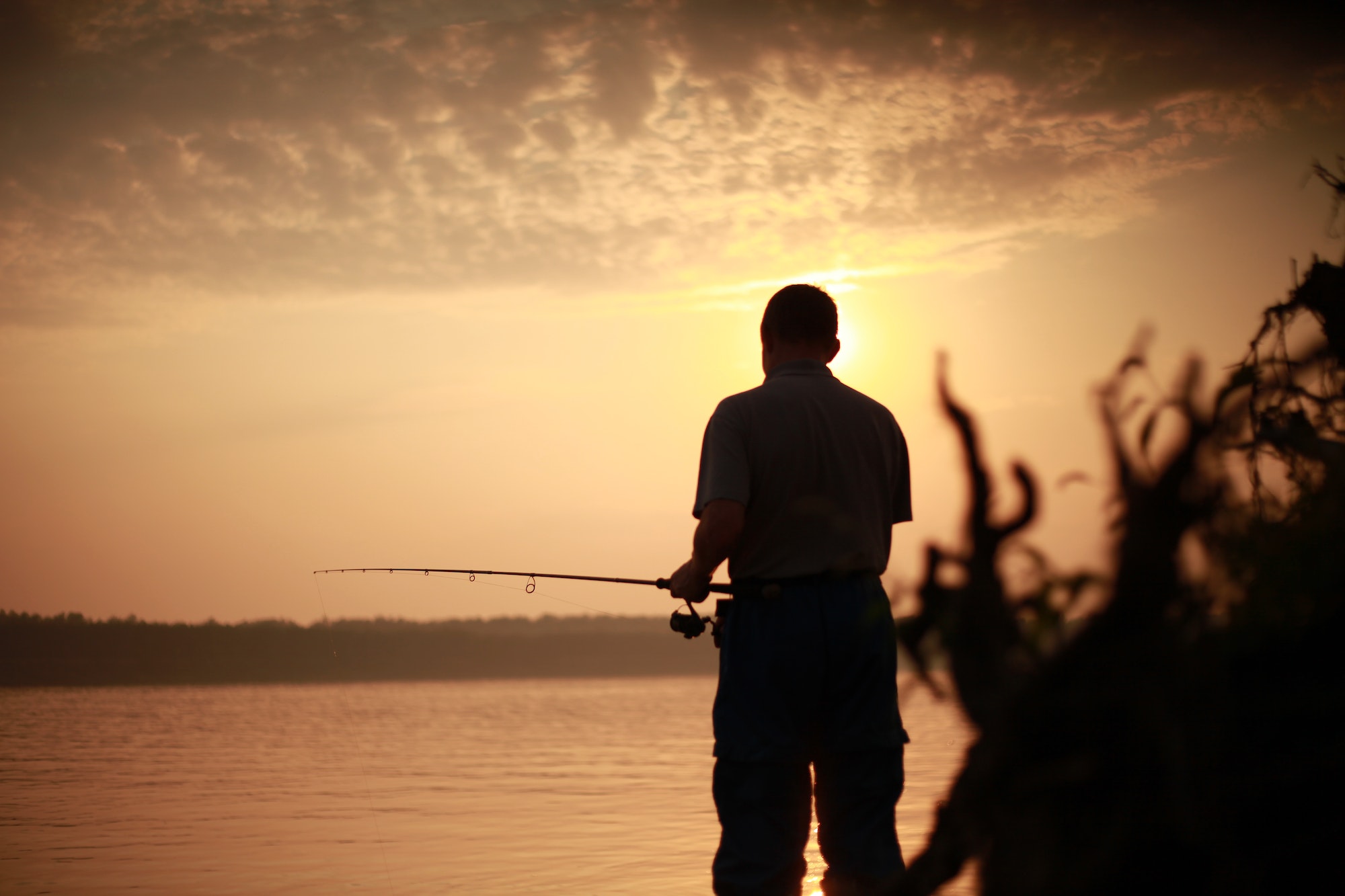 a man at sunset is fishing and fishing on the river with a fishing rod