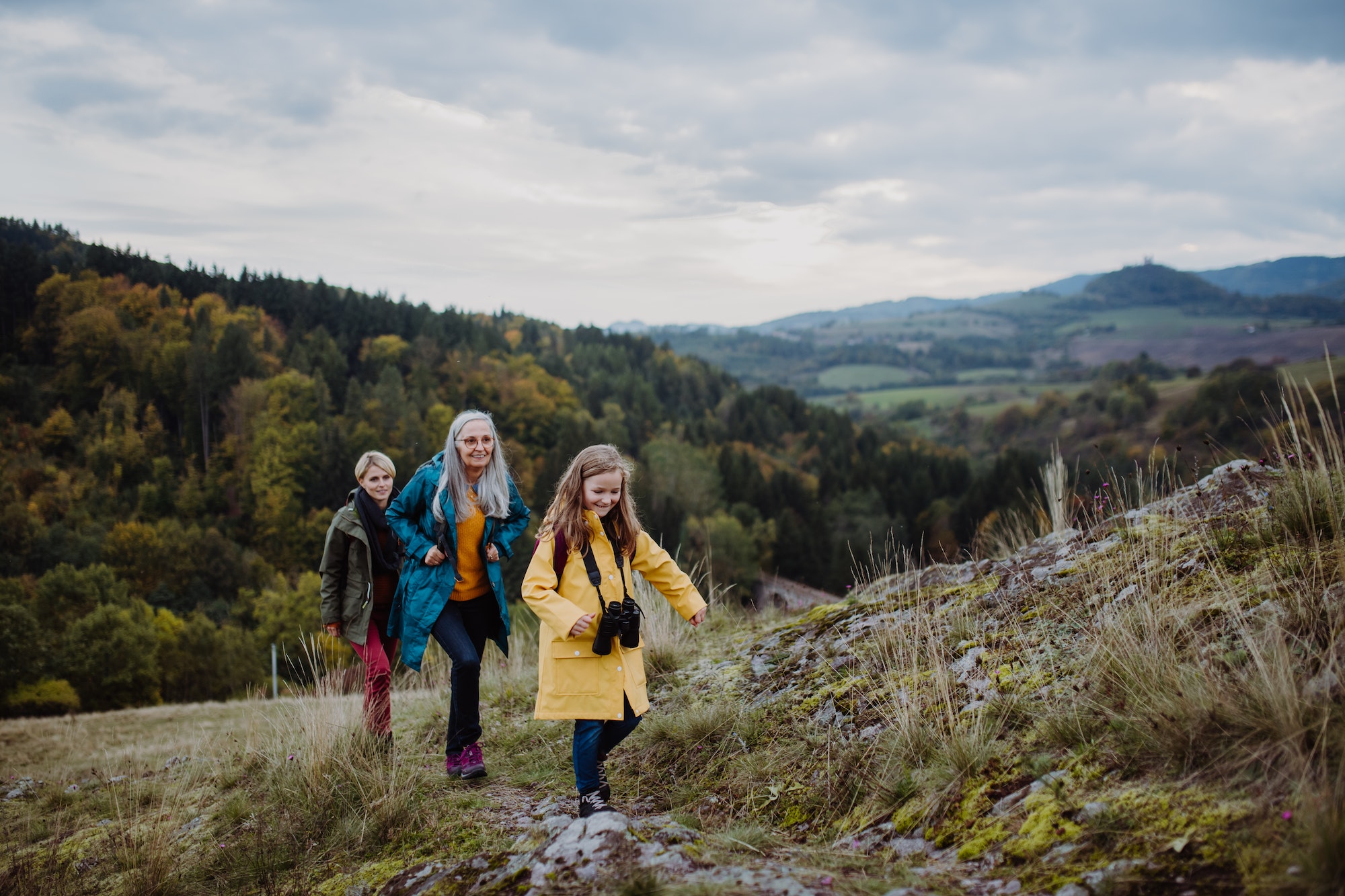 small girl with mother and grandmother hiking outoors in nature